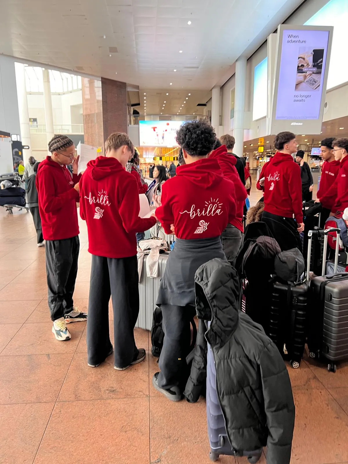 Élèves BRILLA en sweats rouges à l'aéroport de Bruxelles