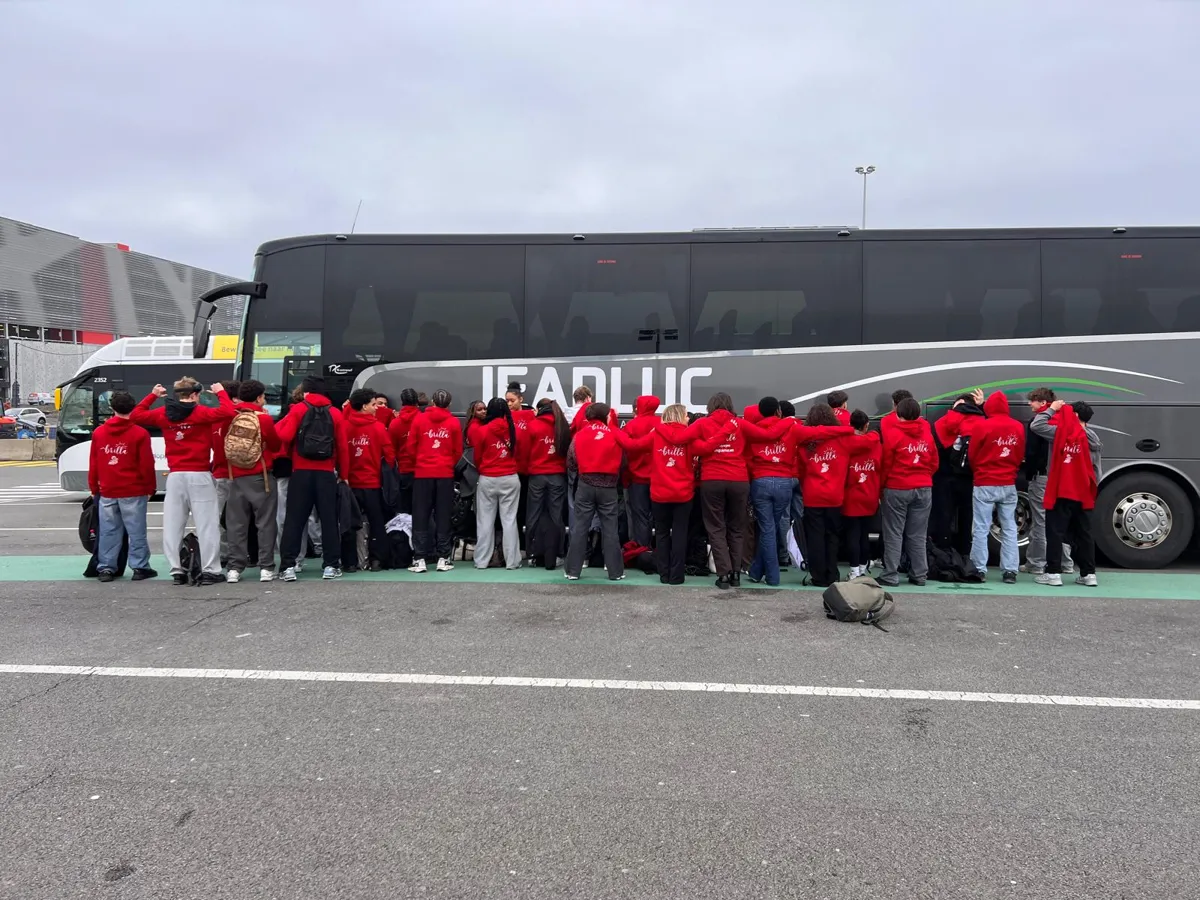 Élèves BRILLA de dos en sweats rouges devant le car
